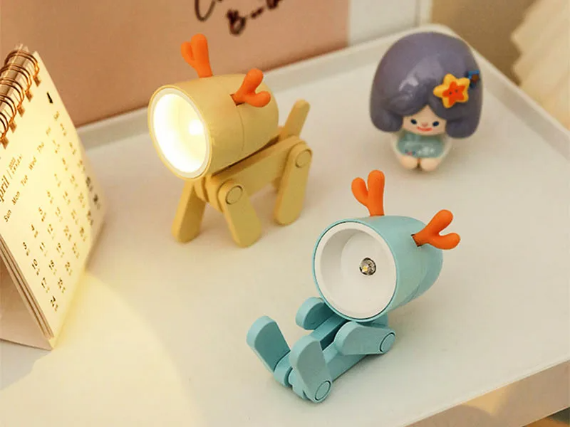 Two cartoon-style deer lamps on a surface with a calendar in the background.