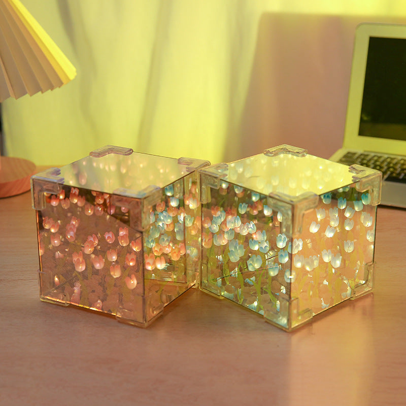 Two LED tulip cubes with multicolored lights, placed on a table surface, likely made of plastic, with a warm light atmosphere in the background.