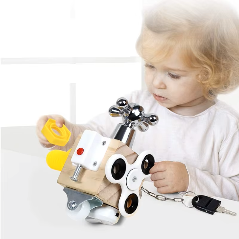 A toddler interacting with a Montessori Motion Learning Busy Cube, which features various mechanical elements such as knobs, switches, and a lock with a key.