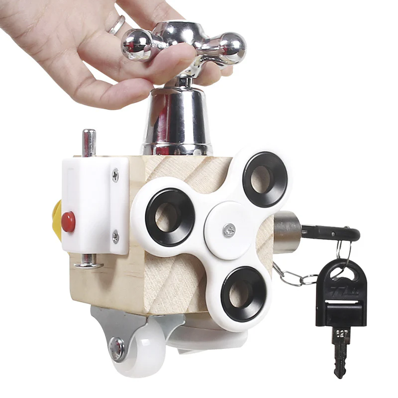 A toddler interacting with a Montessori Motion Learning Busy Cube, which features various mechanical elements such as knobs, switches, and a lock with a key.